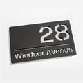 Modern matt black house sign with silver mirror – installed on brick wall