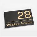 Modern matt black house sign with gold mirror – flat lay product shot