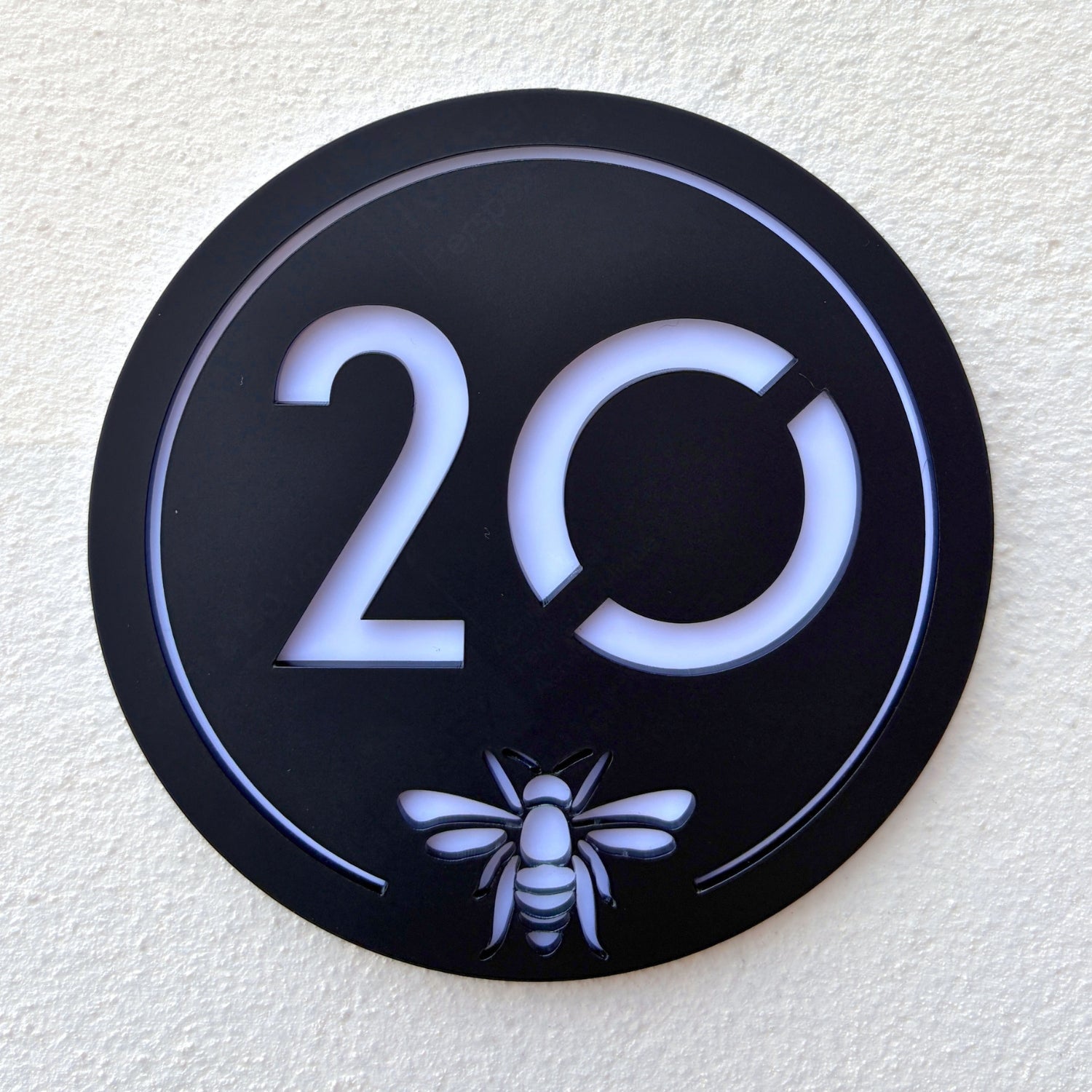 Close-up detail of the Manchester Bee House Sign showing the laser-cut bee emblem and translucent backing