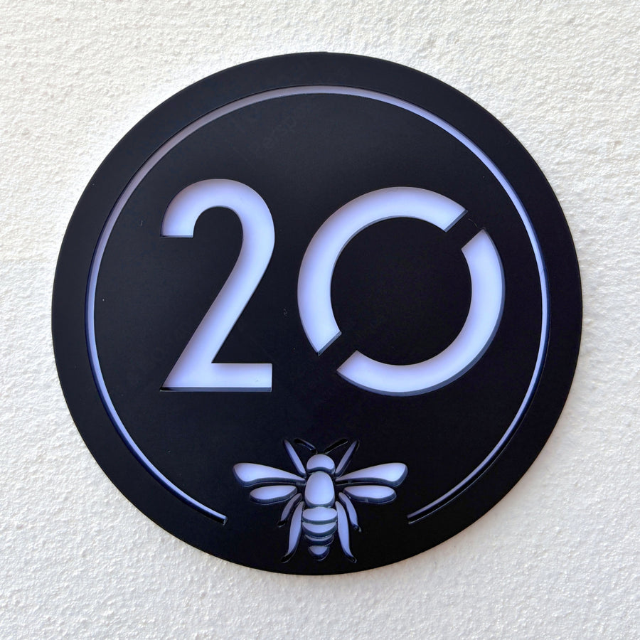 Close-up detail of the Manchester Bee House Sign showing the laser-cut bee emblem and translucent backing