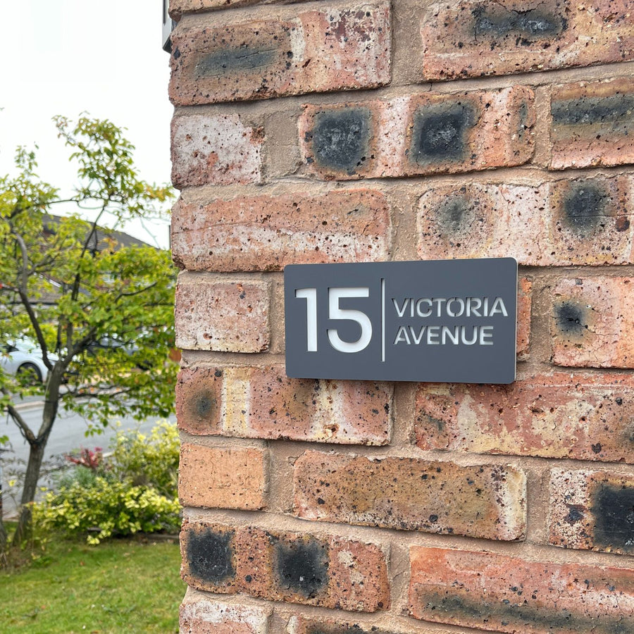 Matt grey rectangle stick on house sign installed on rendered wall