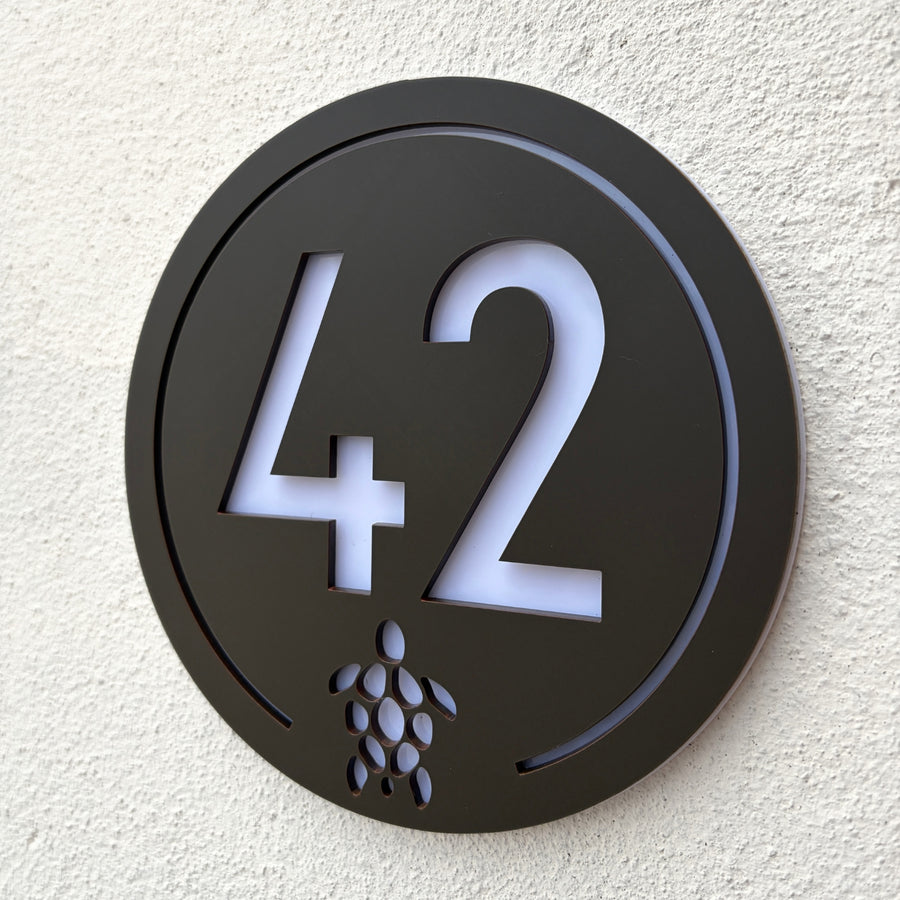 Turtle House Sign in walnut brown mounted on a rendered exterior wall, shown at an angle